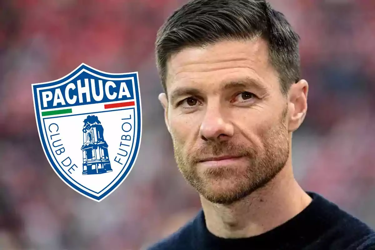 Short-haired, bearded man next to the Pachuca Football Club crest