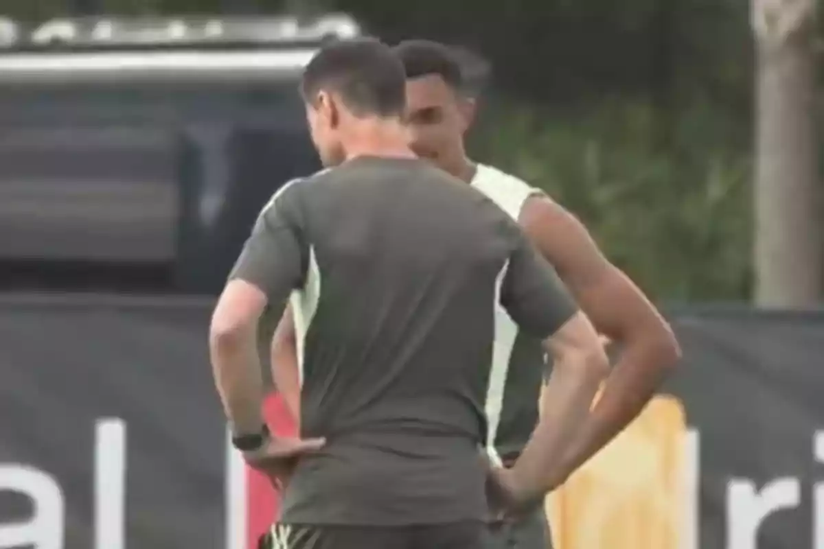 Two people are talking on a sports training field. Two people are talking on a sports training field.