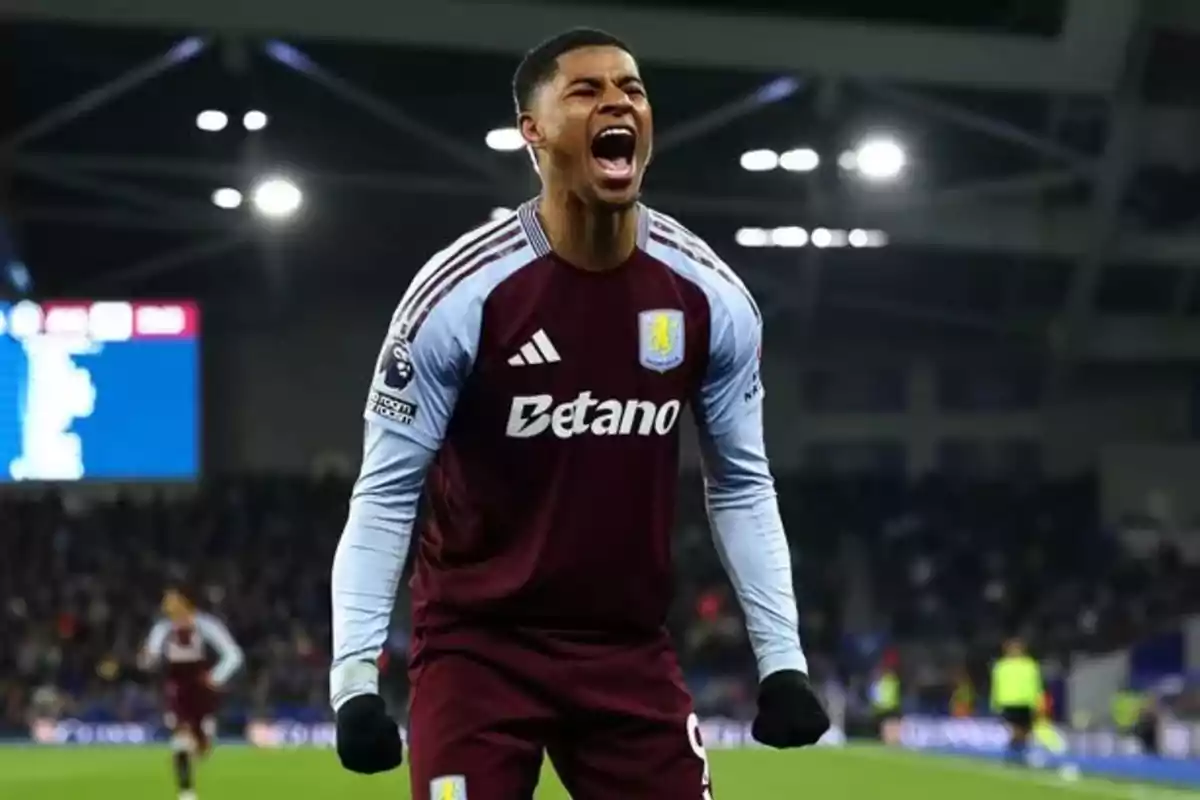 Futbolista del Aston Villa celebrando un gol con expresión de euforia en un estadio iluminado Futbolista del Aston Villa celebrando un gol con expresión de euforia en un estadio iluminado