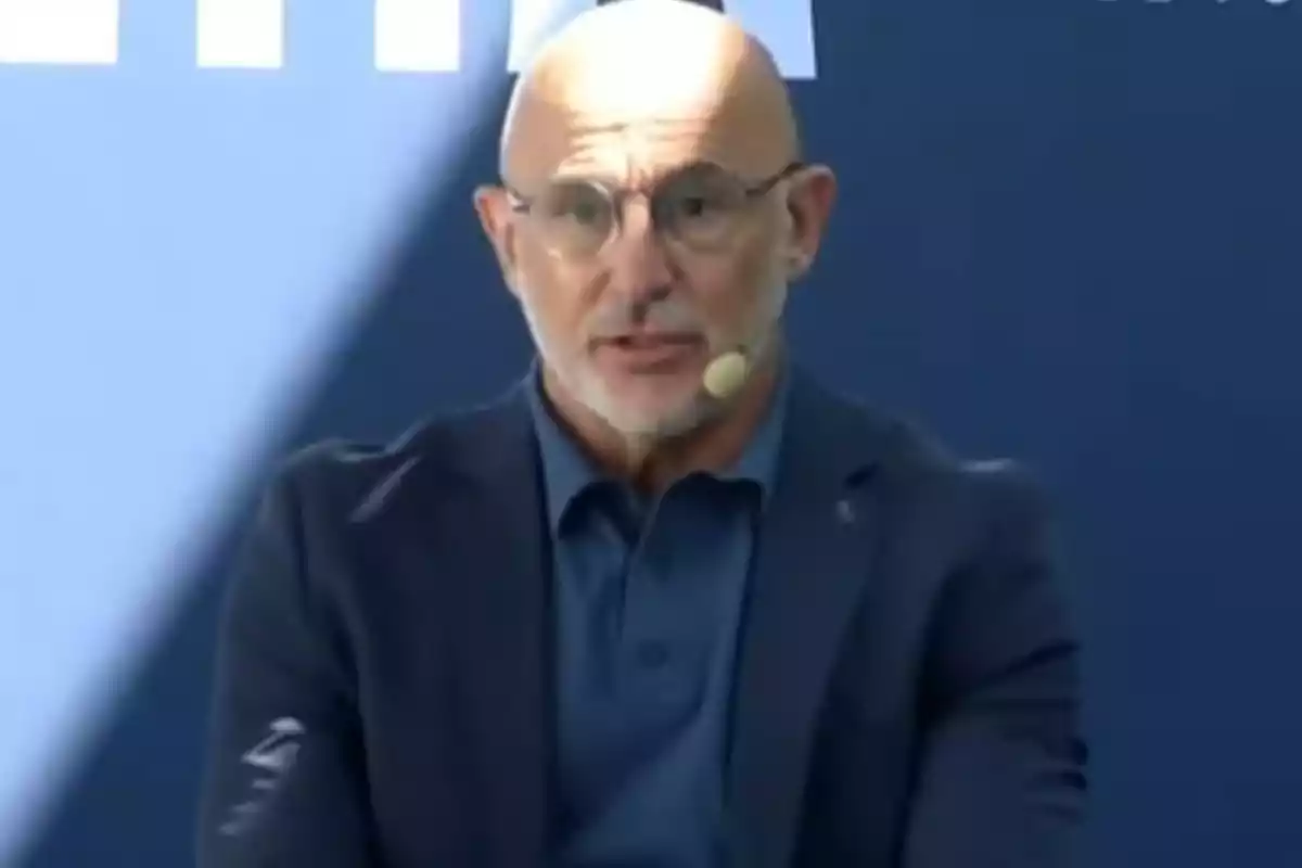 Bald man with glasses and a gray beard wearing a headset microphone and a blue jacket in front of a blue background Bald man with glasses and a gray beard wearing a headset microphone and a blue jacket in front of a blue background
