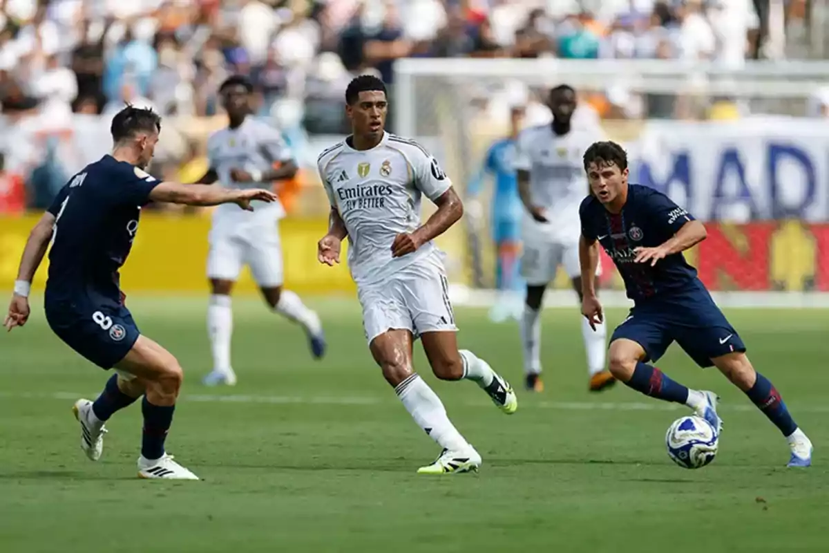 Jugadores de Real Madrid y PSG disputan el balón durante un partido de fútbol en un estadio lleno de espectadores