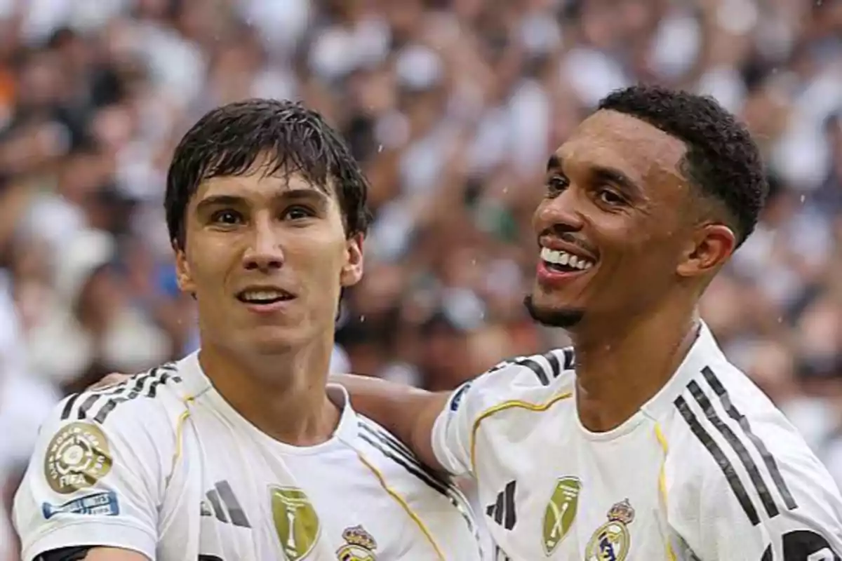 Dos futbolistas del Real Madrid celebran juntos en el campo con expresiones de alegría y camaradería mientras visten el uniforme blanco del equipo Dos futbolistas del Real Madrid celebran juntos en el campo con expresiones de alegría y camaradería mientras visten el uniforme blanco del equipo