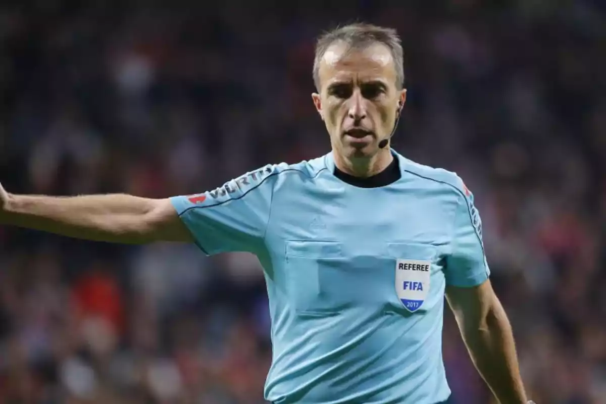 Soccer referee in a light blue uniform during a match pointing with an outstretched arm Soccer referee in a light blue uniform during a match pointing with an outstretched arm