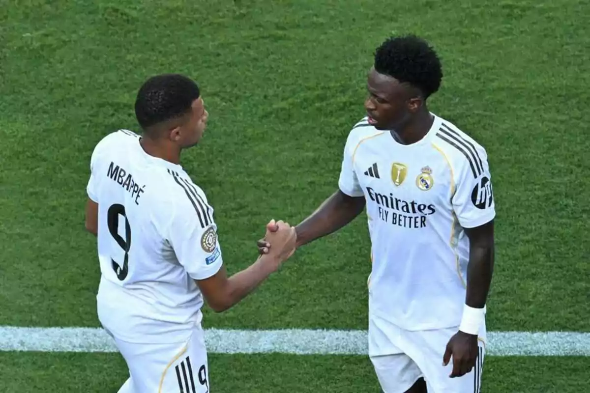Two Real Madrid players in white uniforms greet each other on the field. Two Real Madrid players in white uniforms greet each other on the field.