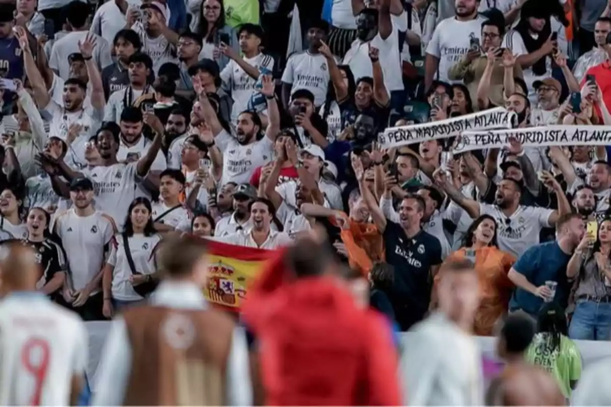 Aficionados del Real Madrid celebran en las gradas de un estadio mostrando bufandas y una bandera de España Aficionados del Real Madrid celebran en las gradas de un estadio mostrando bufandas y una bandera de España