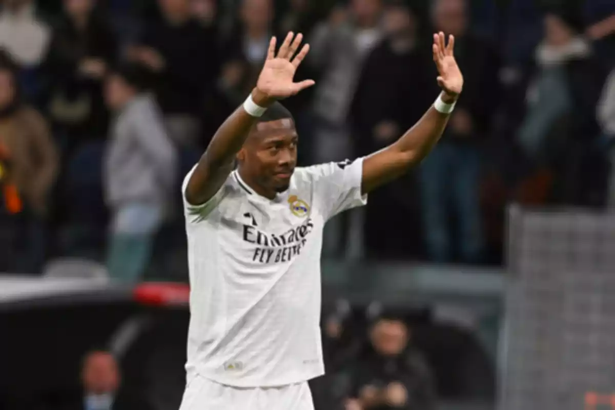 Futbolista del Real Madrid levantando ambas manos en señal de saludo durante un partido con el público de fondo. Futbolista del Real Madrid levantando ambas manos en señal de saludo durante un partido con el público de fondo.