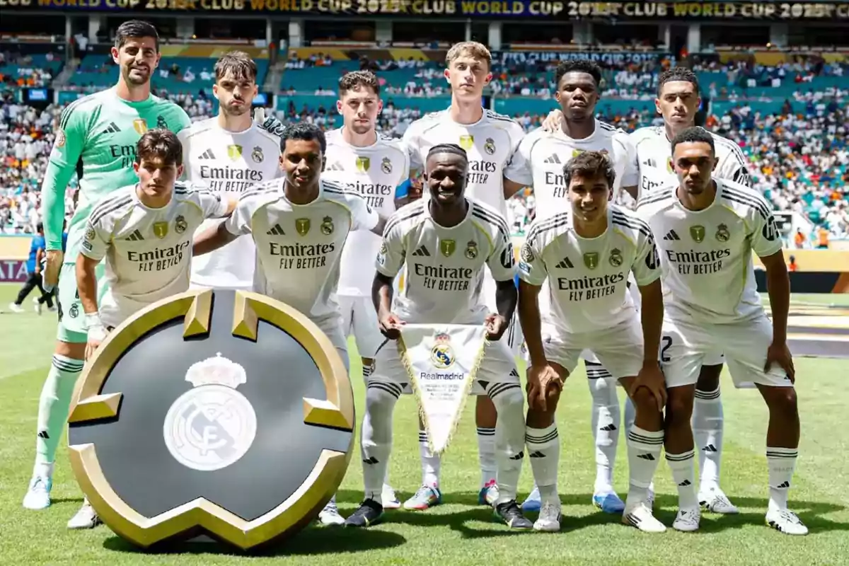 Eleven Real Madrid players pose on the field before a match wearing the white uniform and a large club crest on the front.