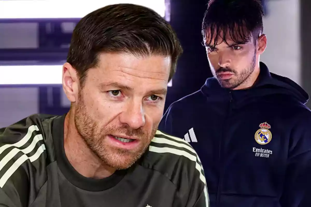 Dos hombres con ropa deportiva del Real Madrid uno en primer plano hablando y otro al fondo con sudadera azul marino