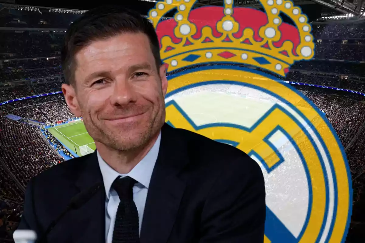 Hombre sonriente con traje frente al escudo del Real Madrid y un estadio lleno de aficionados