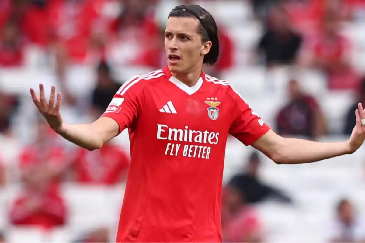 Futbolista con uniforme rojo del Benfica gesticulando con los brazos abiertos en un estadio Futbolista con uniforme rojo del Benfica gesticulando con los brazos abiertos en un estadio