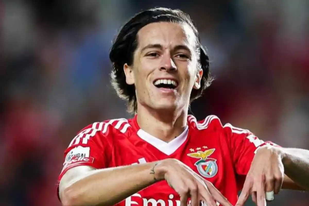 Soccer player wearing a red Benfica jersey celebrating a goal with a big smile on his face Soccer player wearing a red Benfica jersey celebrating a goal with a big smile on his face