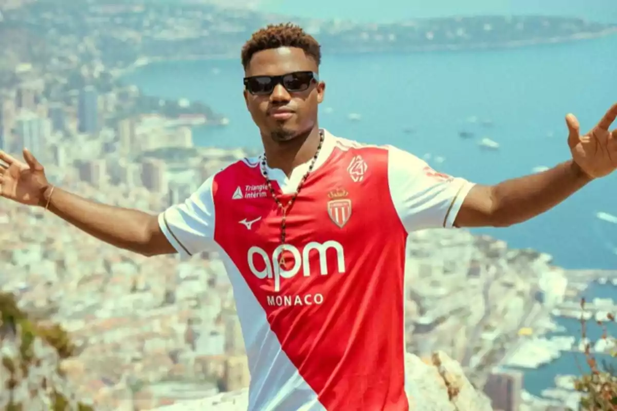 Man wearing sunglasses and an AS Monaco jersey posing with arms outstretched in front of a panoramic view of a coastal city Man wearing sunglasses and an AS Monaco jersey posing with arms outstretched in front of a panoramic view of a coastal city