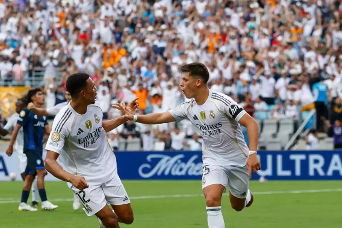 Two Real Madrid players celebrate a goal on the field while the fans applaud and cheer in the stands. Two Real Madrid players celebrate a goal on the field while the fans applaud and cheer in the stands.