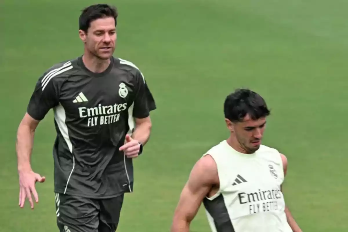 Dos personas con ropa de entrenamiento del Real Madrid corren sobre el césped durante una práctica Dos personas con ropa de entrenamiento del Real Madrid corren sobre el césped durante una práctica