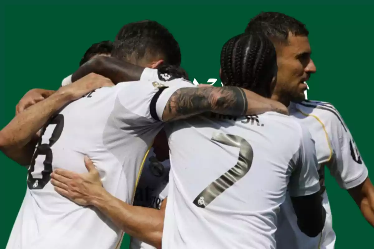 Jugadores de fútbol con uniforme blanco celebran abrazados sobre un fondo verde
