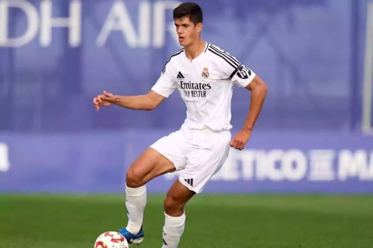 Futbolista con uniforme blanco controlando el balón en un campo de juego durante un partido Futbolista con uniforme blanco controlando el balón en un campo de juego durante un partido