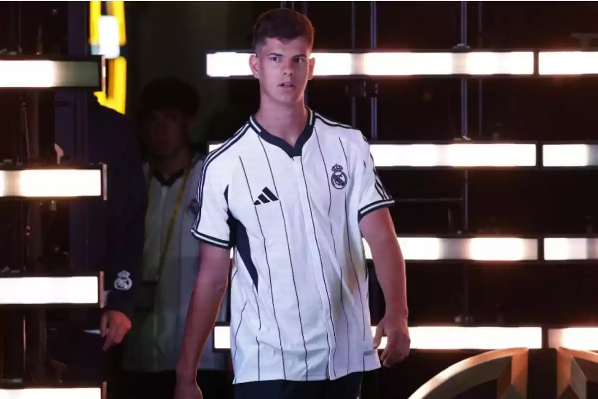 Young man in a white Real Madrid jersey walking on a lit stage Young man in a white Real Madrid jersey walking on a lit stage