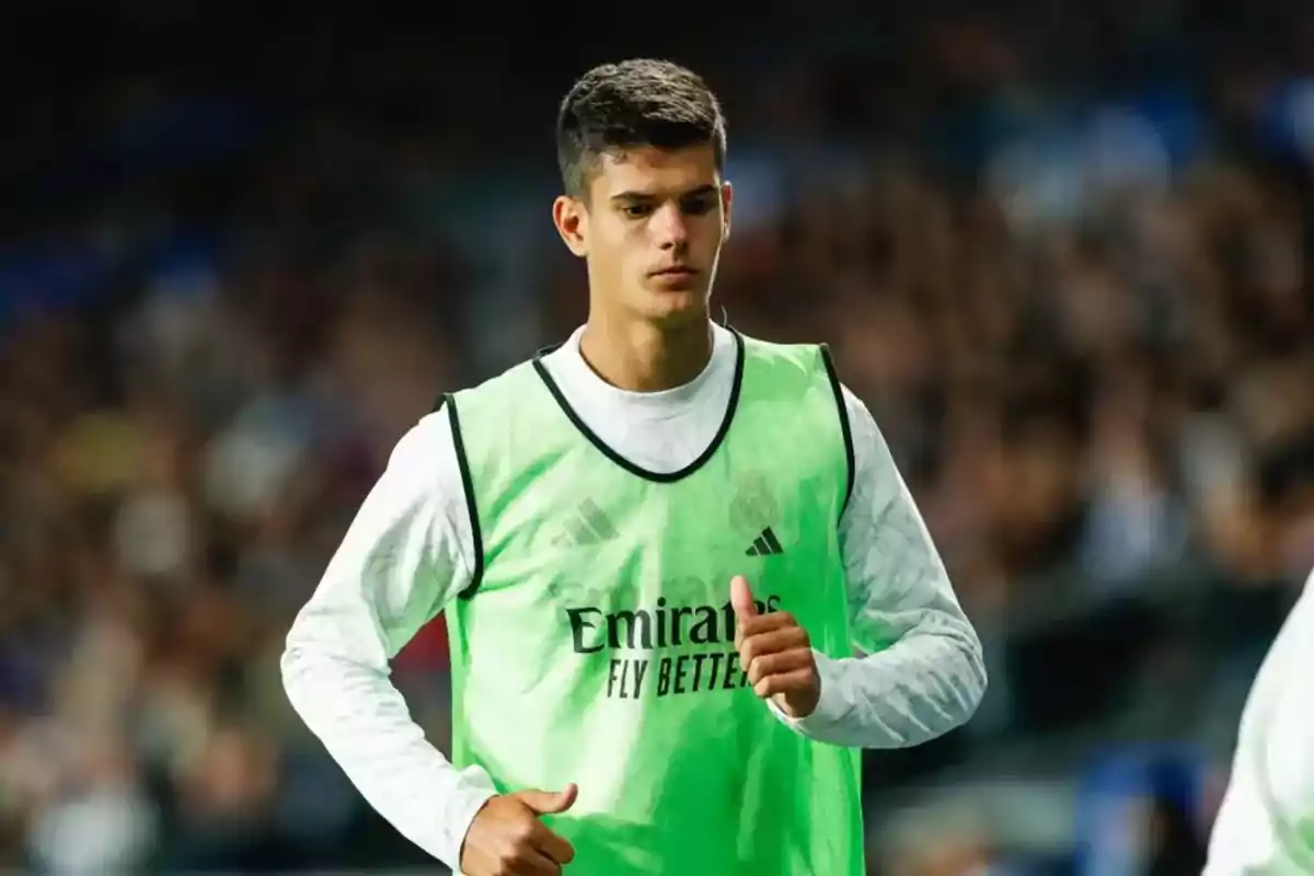 Young player wearing a green training bib and a white jersey during warm-up in a stadium Young player wearing a green training bib and a white jersey during warm-up in a stadium