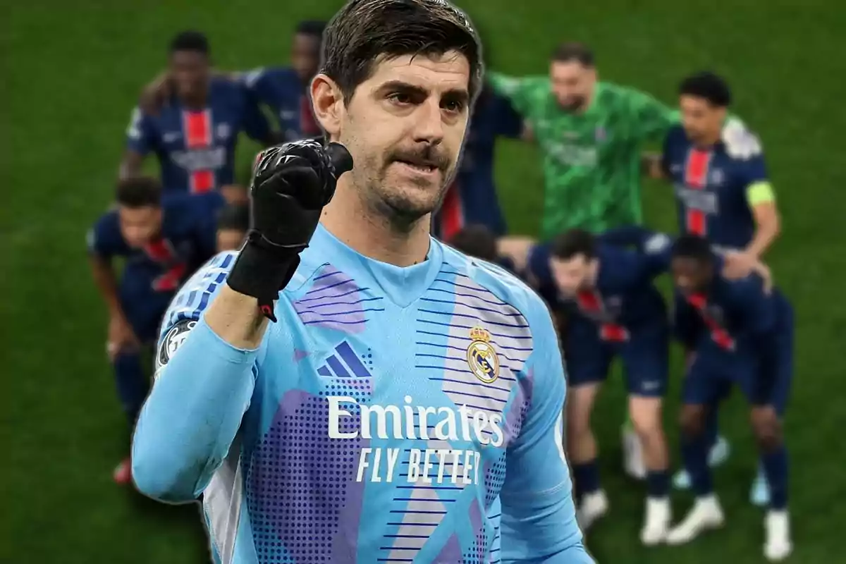 Real Madrid goalkeeper celebrating with his fist raised while PSG players pose out of focus in the background on the soccer field