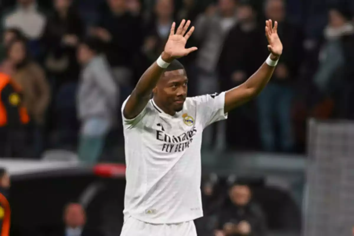 Futbolista del Real Madrid levantando ambas manos en señal de saludo durante un partido con público de fondo Futbolista del Real Madrid levantando ambas manos en señal de saludo durante un partido con público de fondo