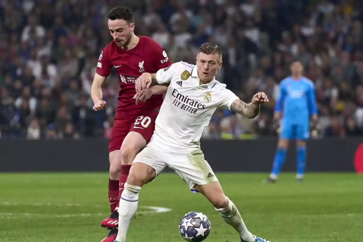 Dos futbolistas disputan el balón durante un partido entre Real Madrid y Liverpool en un estadio lleno de espectadores Dos futbolistas disputan el balón durante un partido entre Real Madrid y Liverpool en un estadio lleno de espectadores