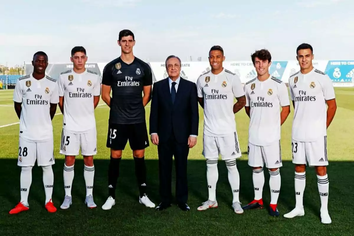 Group of Real Madrid players posing with a man in a suit on a training field Group of Real Madrid players posing with a man in a suit on a training field