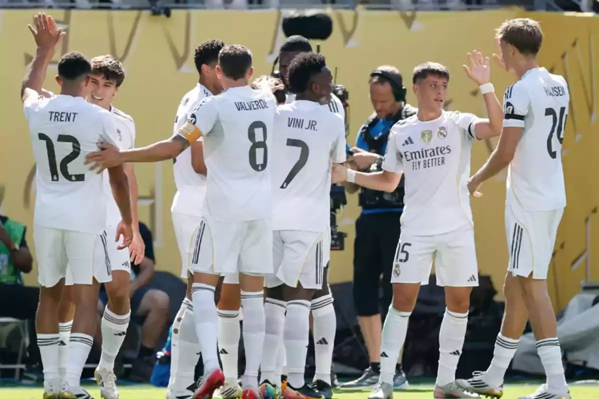 Jugadores de un equipo de fútbol celebran juntos en el campo con uniformes blancos