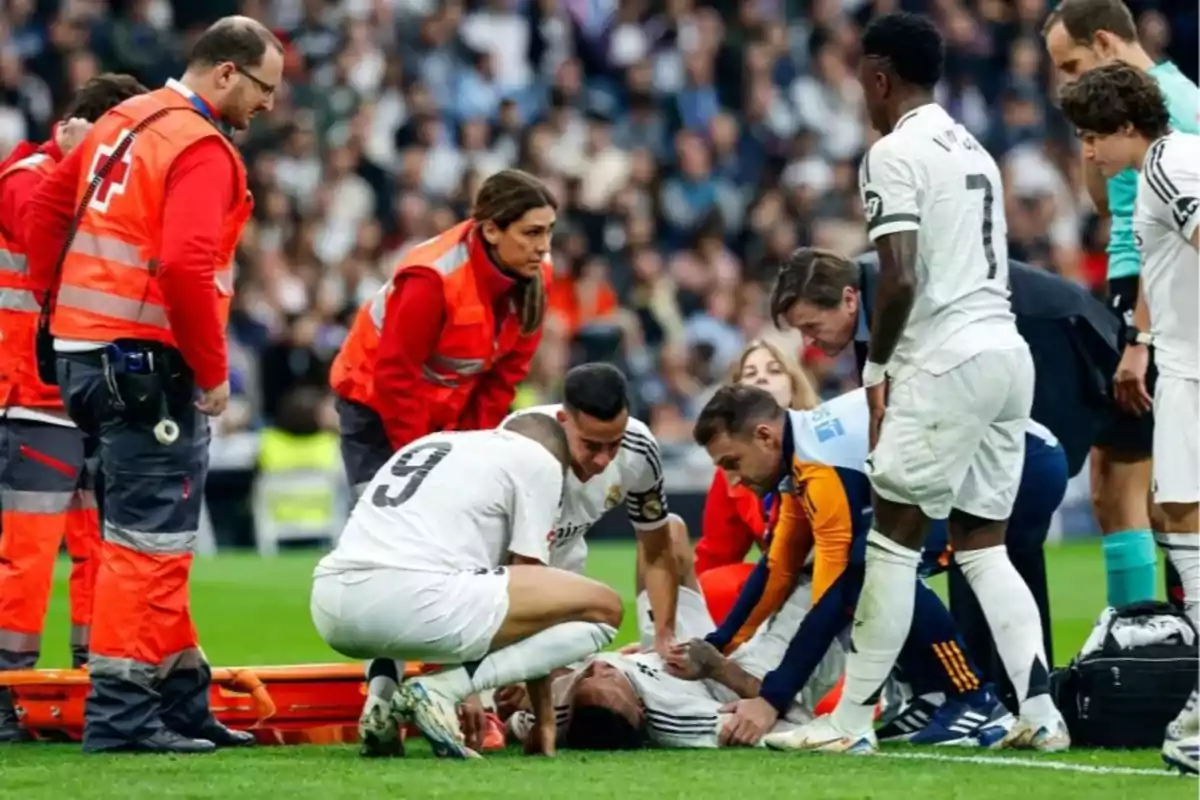 Varios jugadores y personal médico atienden a un futbolista lesionado en el campo durante un partido de fútbol. Varios jugadores y personal médico atienden a un futbolista lesionado en el campo durante un partido de fútbol.