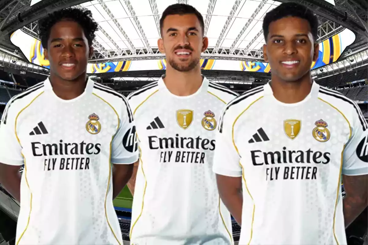Tres futbolistas con uniforme blanco del Real Madrid posan en un estadio cubierto