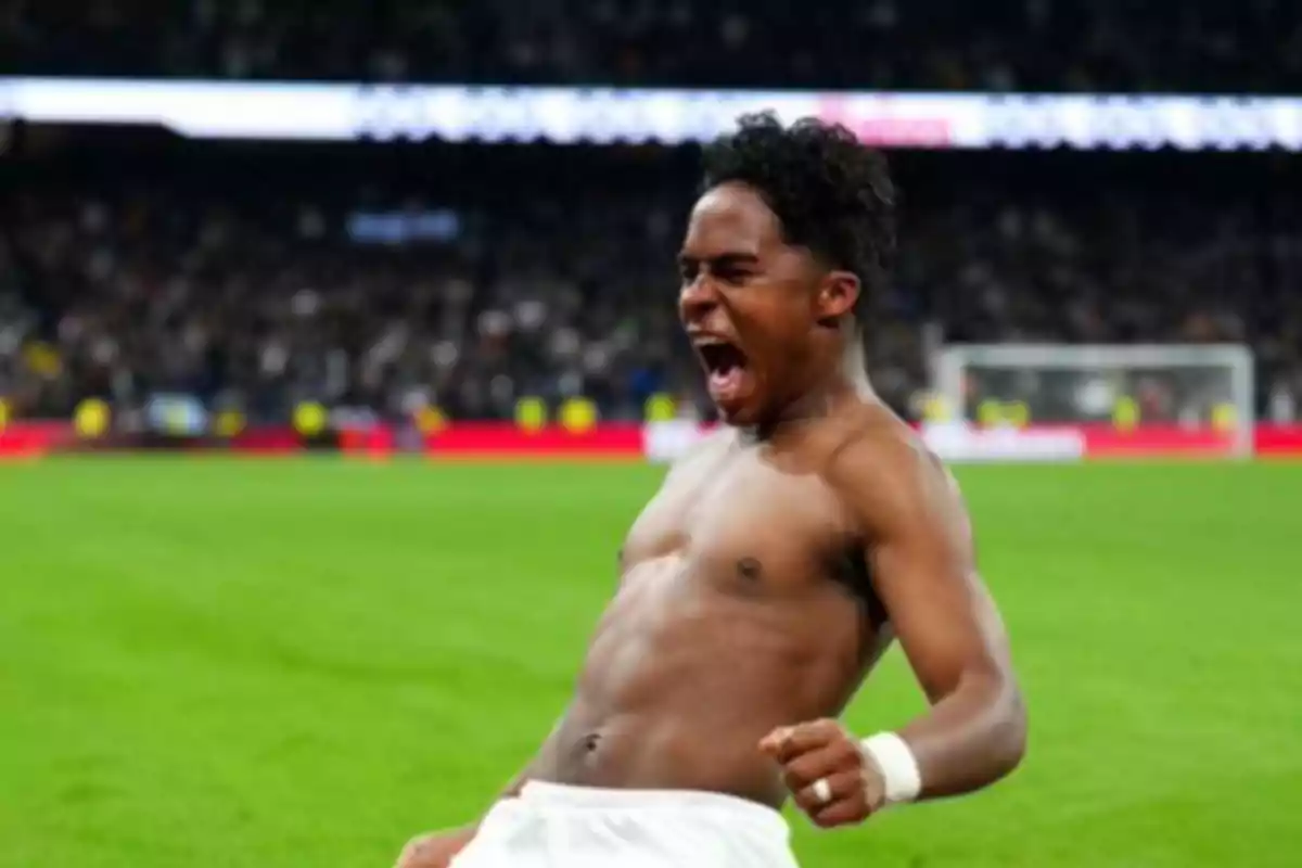 Jugador de fútbol celebrando efusivamente sin camiseta en el campo tras anotar un gol Jugador de fútbol celebrando efusivamente sin camiseta en el campo tras anotar un gol