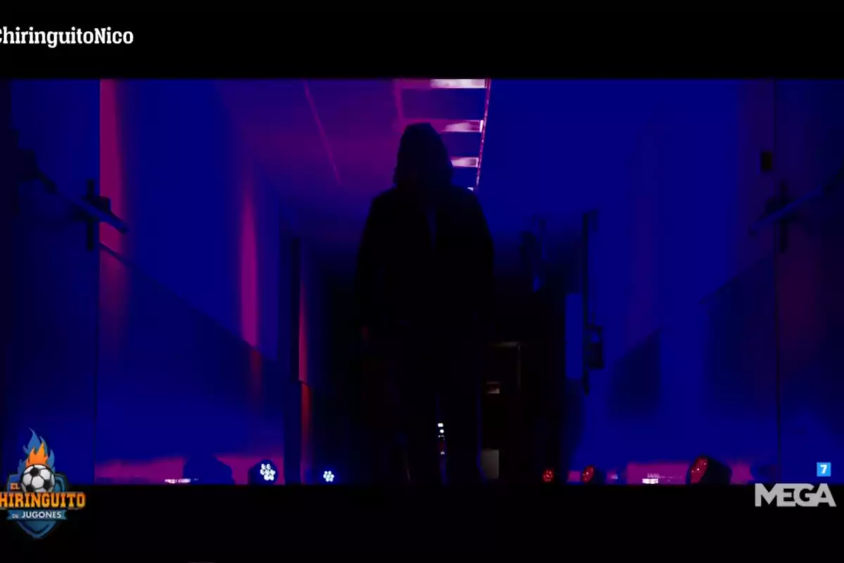Hooded person walking down a hallway lit with blue and pink lights