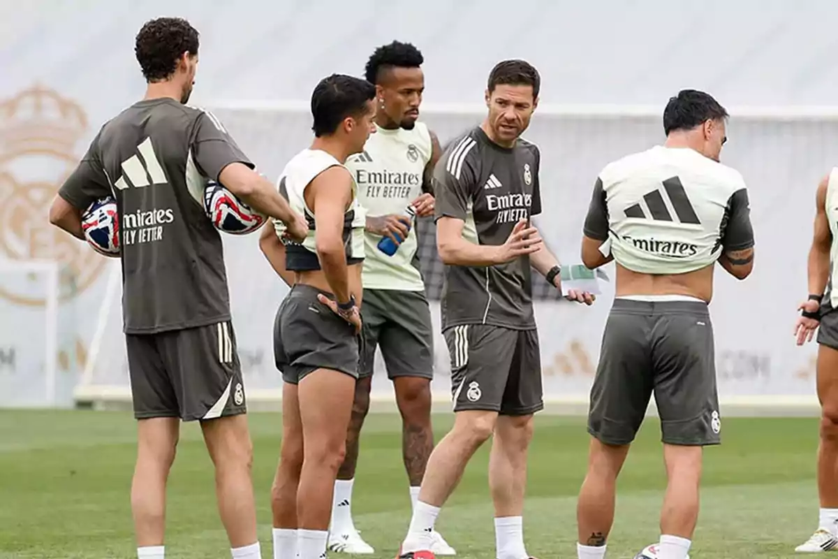 Un grupo de jugadores y un entrenador del Real Madrid conversan en el campo de entrenamiento durante una práctica de fútbol Un grupo de jugadores y un entrenador del Real Madrid conversan en el campo de entrenamiento durante una práctica de fútbol