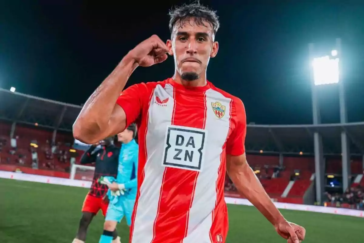 Soccer player in a red and white uniform celebrating in a lit-up stadium Soccer player in a red and white uniform celebrating in a lit-up stadium
