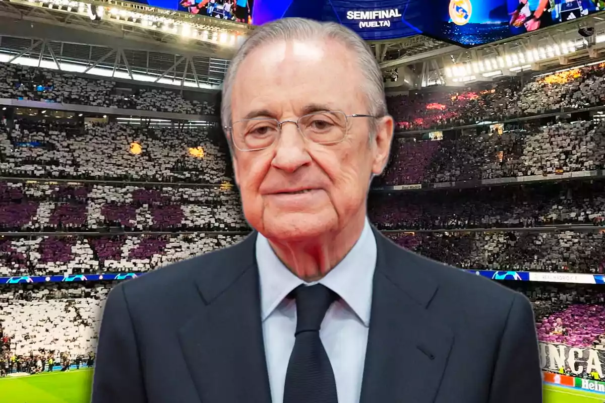Older man with glasses and a dark suit in a football stadium full of fans