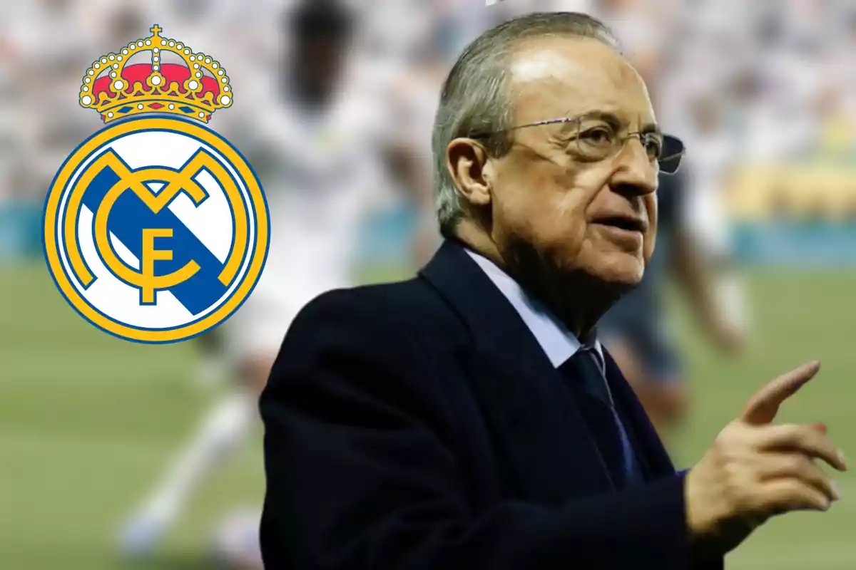 Man in a suit pointing with his finger and the Real Madrid crest in the background