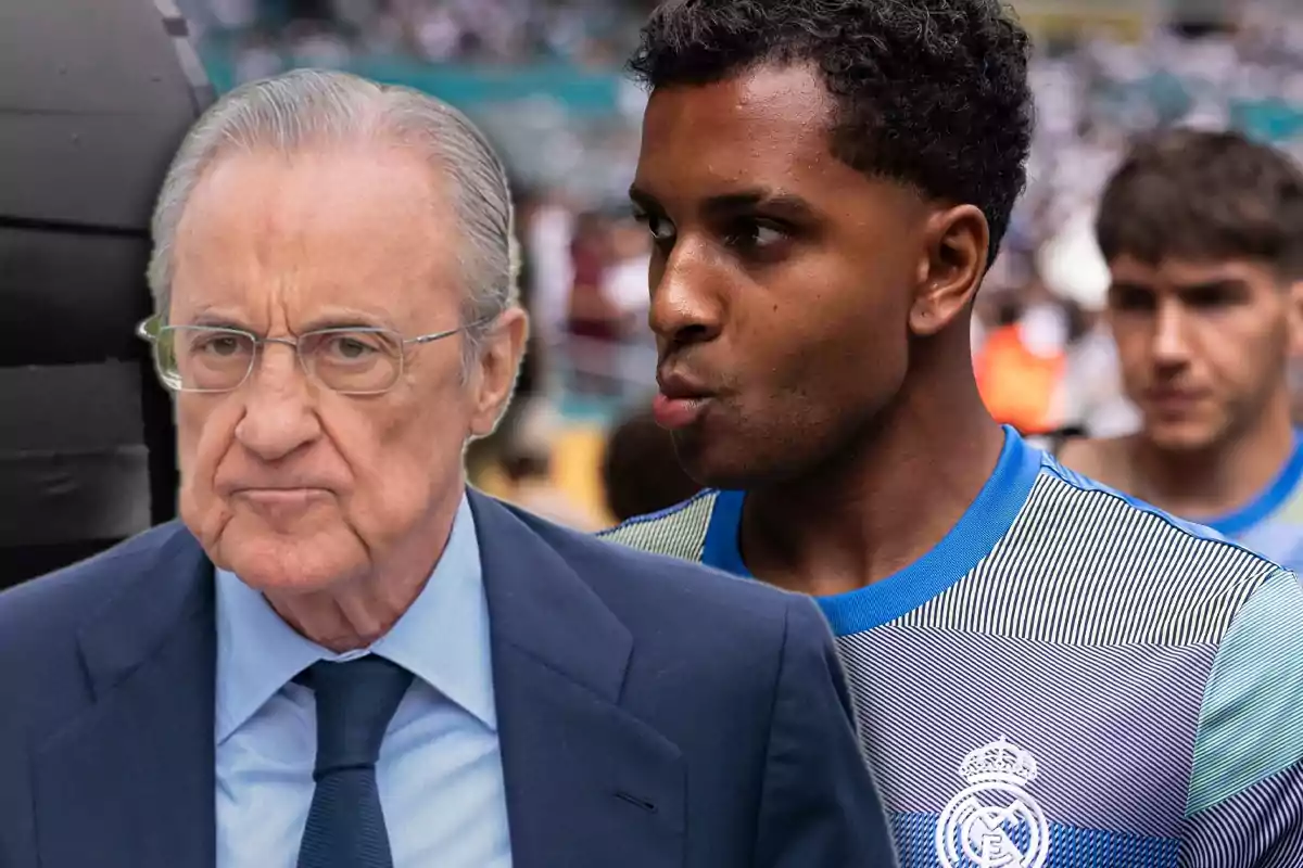Un hombre mayor con gafas y traje azul junto a un futbolista con camiseta de entrenamiento del Real Madrid en un estadio lleno de gente.