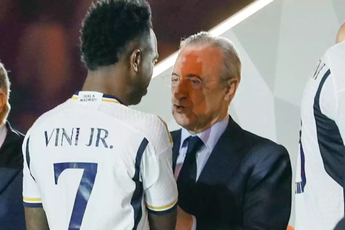Soccer player with the number 7 and the name Vini Jr. on the jersey talking to a man in a suit at a sporting event Soccer player with the number 7 and the name Vini Jr. on the jersey talking to a man in a suit at a sporting event