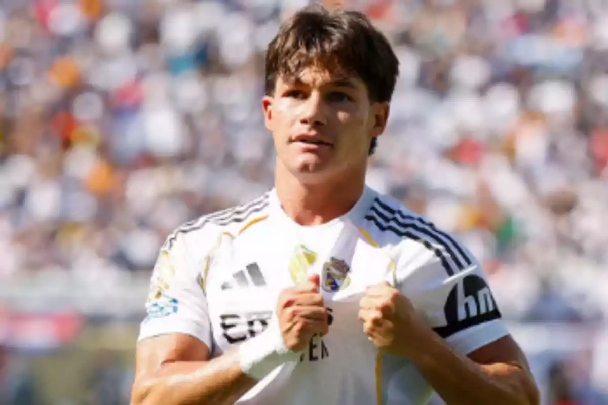Futbolista con uniforme blanco celebrando en un estadio lleno de aficionados Futbolista con uniforme blanco celebrando en un estadio lleno de aficionados