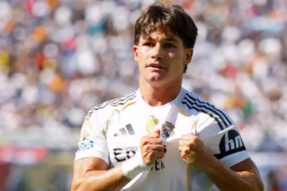 Futbolista con uniforme blanco celebrando en un estadio lleno de aficionados