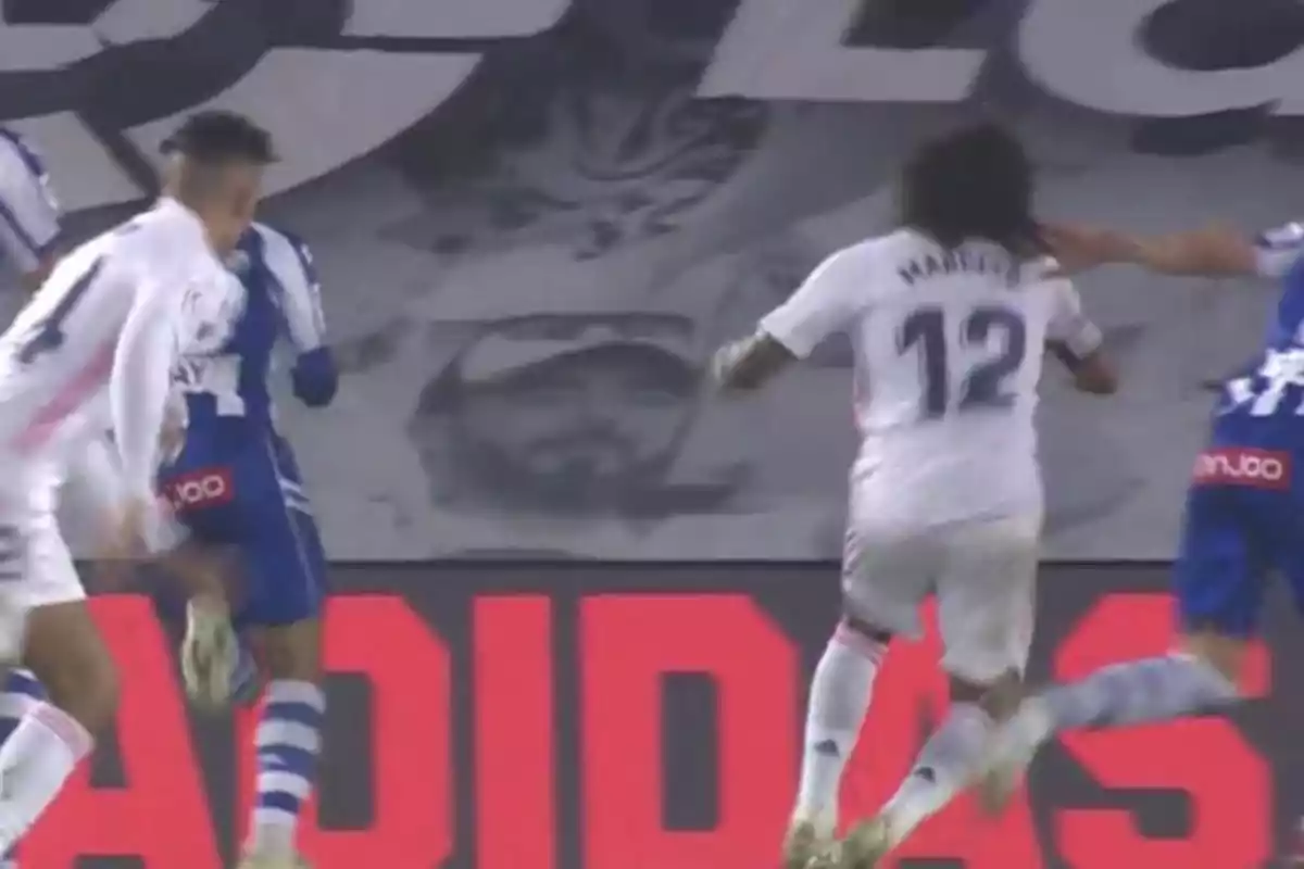 Jugadores de fútbol en acción durante un partido con un mural en blanco y negro de fondo y un letrero publicitario rojo en la parte inferior Jugadores de fútbol en acción durante un partido con un mural en blanco y negro de fondo y un letrero publicitario rojo en la parte inferior
