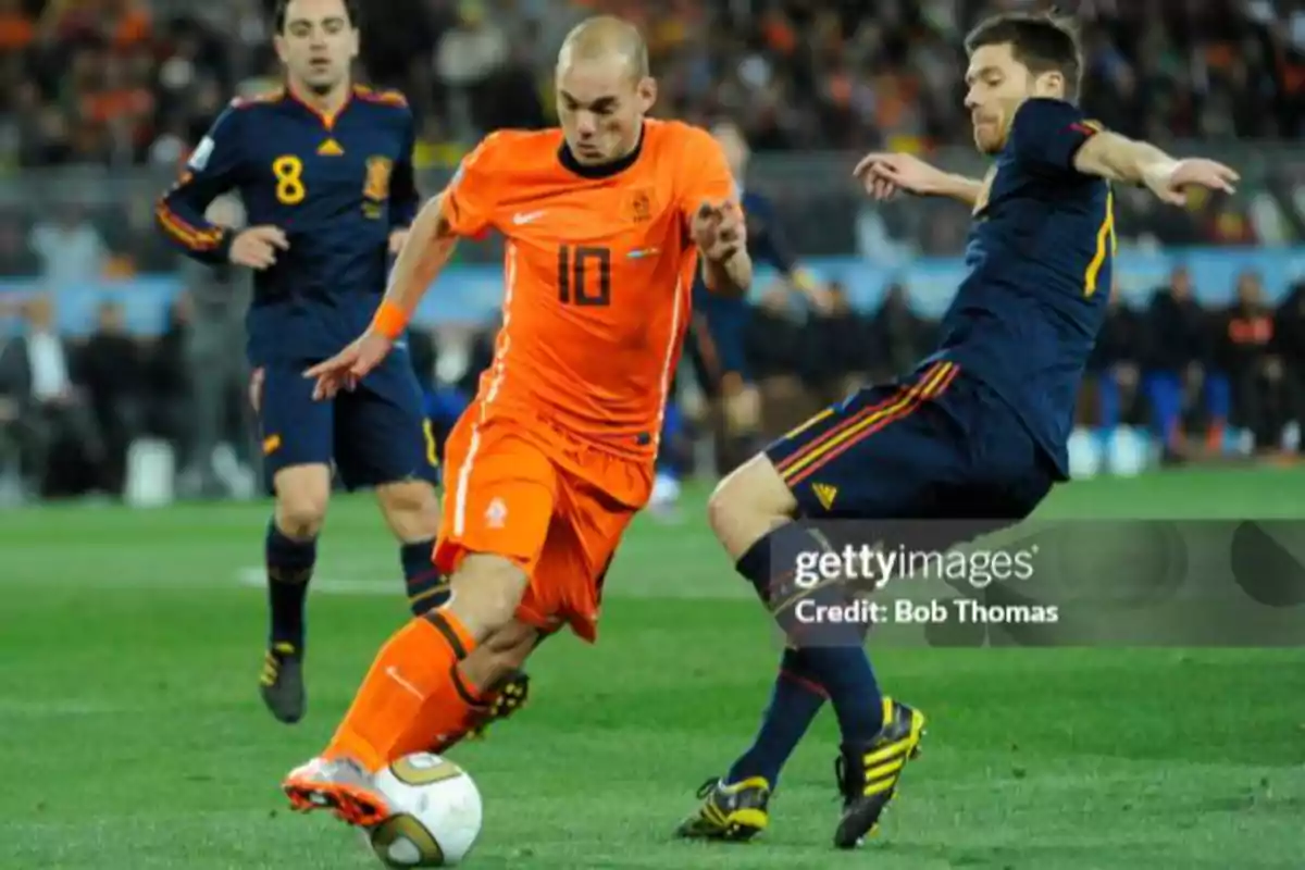 Jugador de la selección de Países Bajos controla el balón mientras un futbolista de España intenta quitarle la pelota durante un partido de fútbol Jugador de la selección de Países Bajos controla el balón mientras un futbolista de España intenta quitarle la pelota durante un partido de fútbol