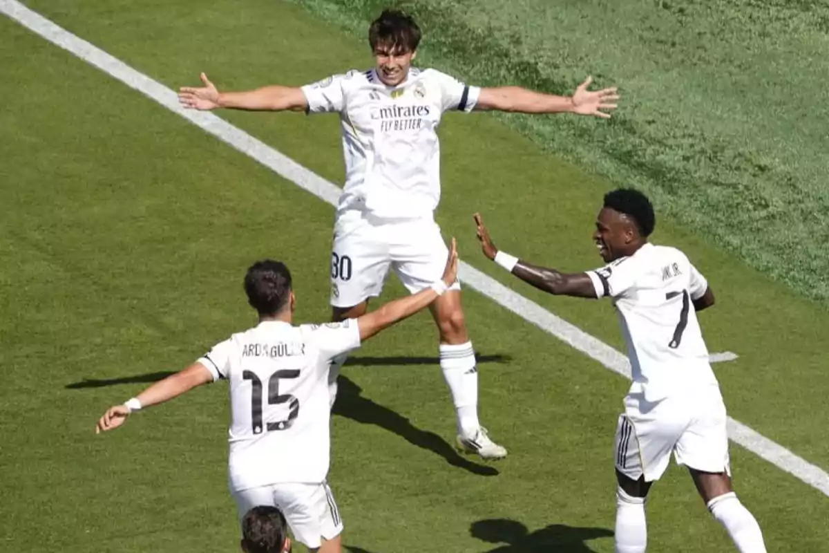 Tres jugadores del Real Madrid celebran un gol en el campo de fútbol con gestos de alegría y los brazos extendidos Tres jugadores del Real Madrid celebran un gol en el campo de fútbol con gestos de alegría y los brazos extendidos