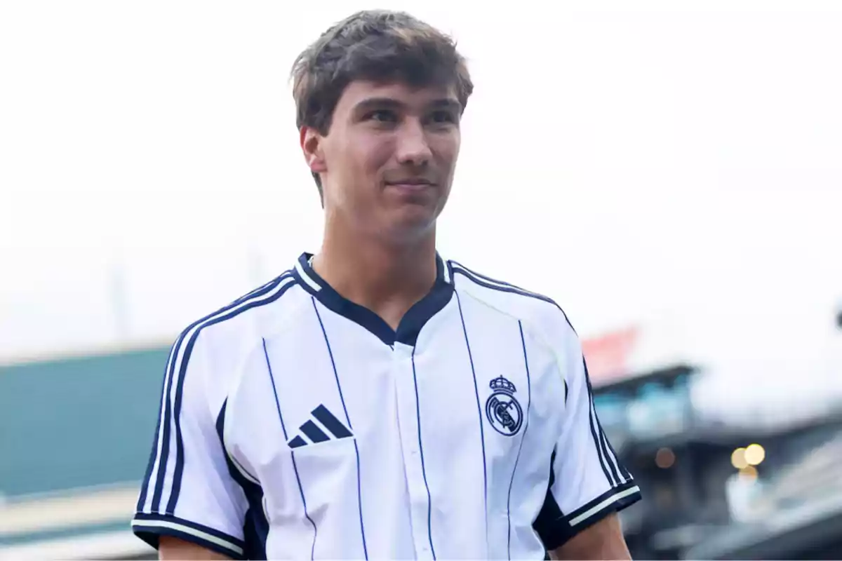 Joven con camiseta blanca de fútbol del Real Madrid en un estadio al aire libre Joven con camiseta blanca de fútbol del Real Madrid en un estadio al aire libre