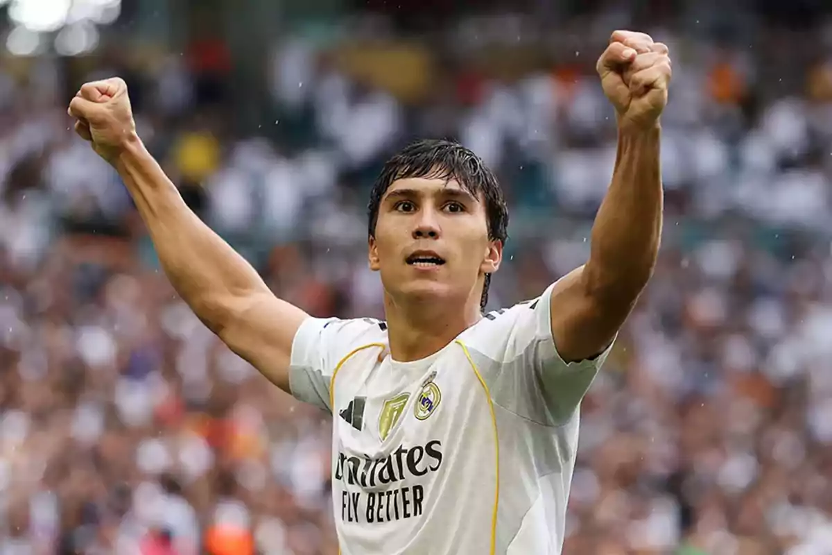 Real Madrid player celebrating with arms raised in a stadium full of fans
