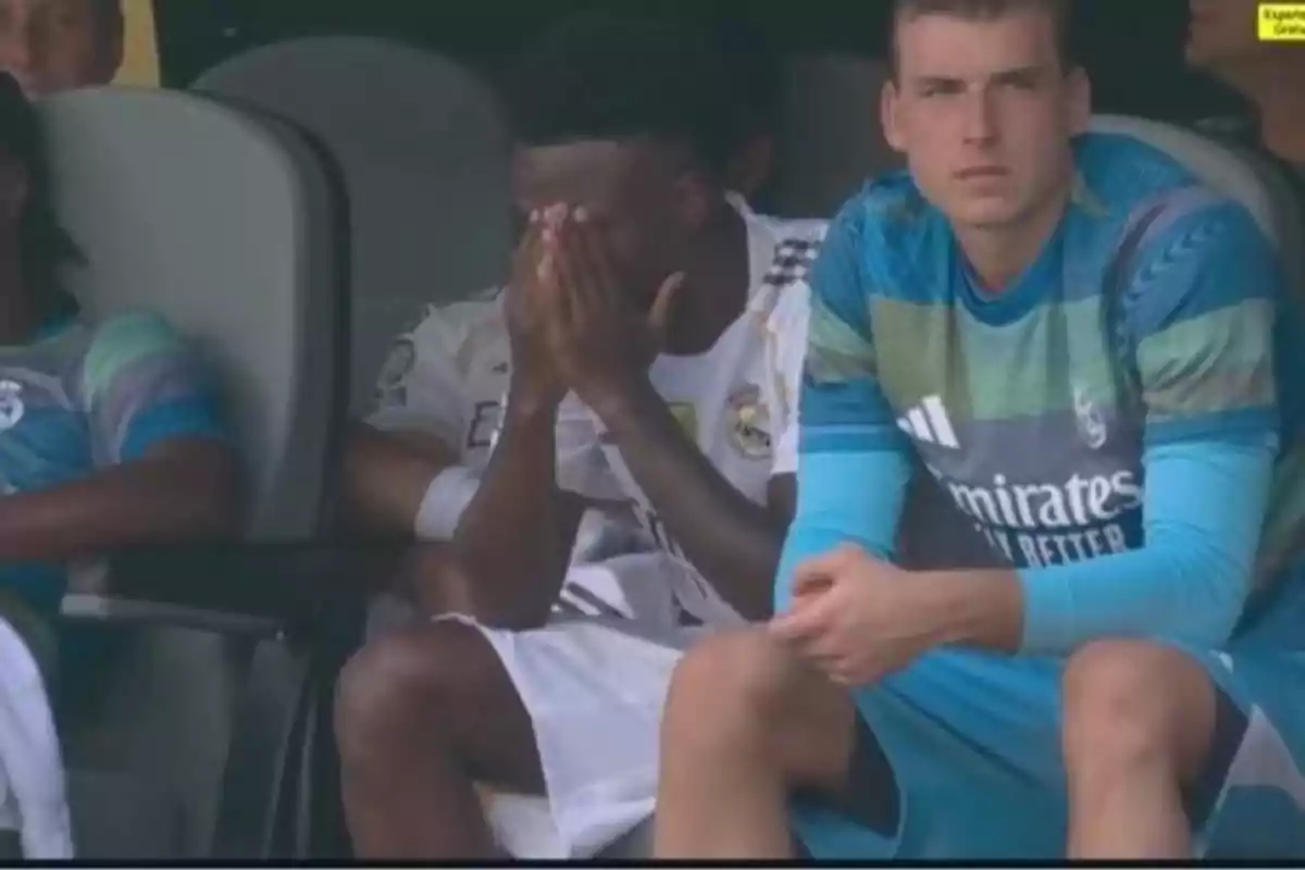Real Madrid players sitting on the bench, one of them covering his face with his hands, showing an expression of frustration or sadness.