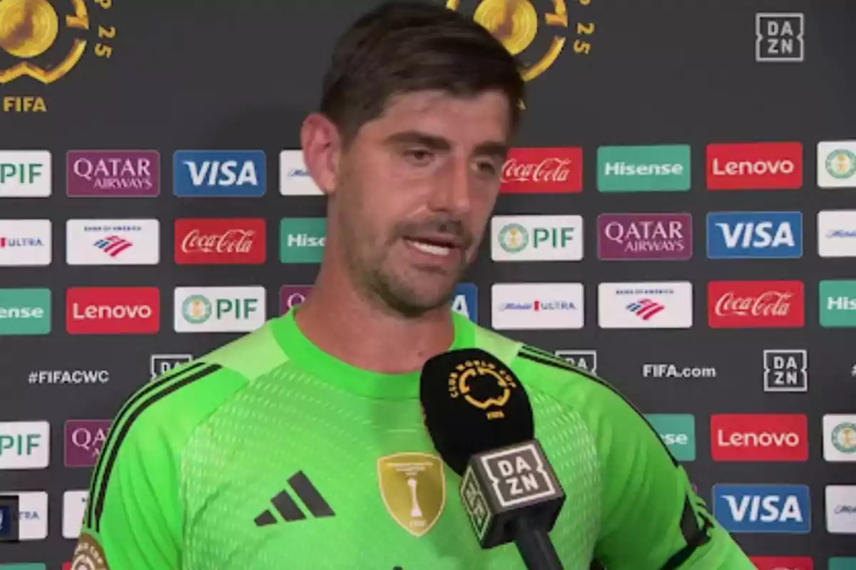 Portero de fútbol con uniforme verde dando una entrevista frente a un fondo con logotipos de patrocinadores y el micrófono de DAZN