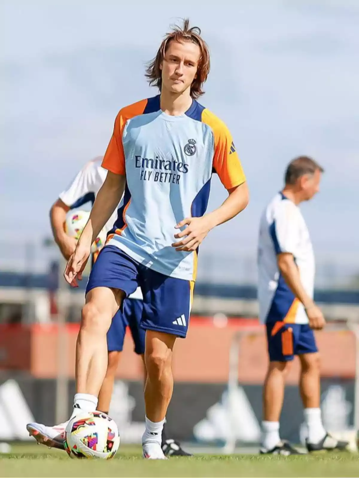 Futbolista entrenando en un campo de fútbol con uniforme de entrenamiento del Real Madrid mientras controla un balón Futbolista entrenando en un campo de fútbol con uniforme de entrenamiento del Real Madrid mientras controla un balón