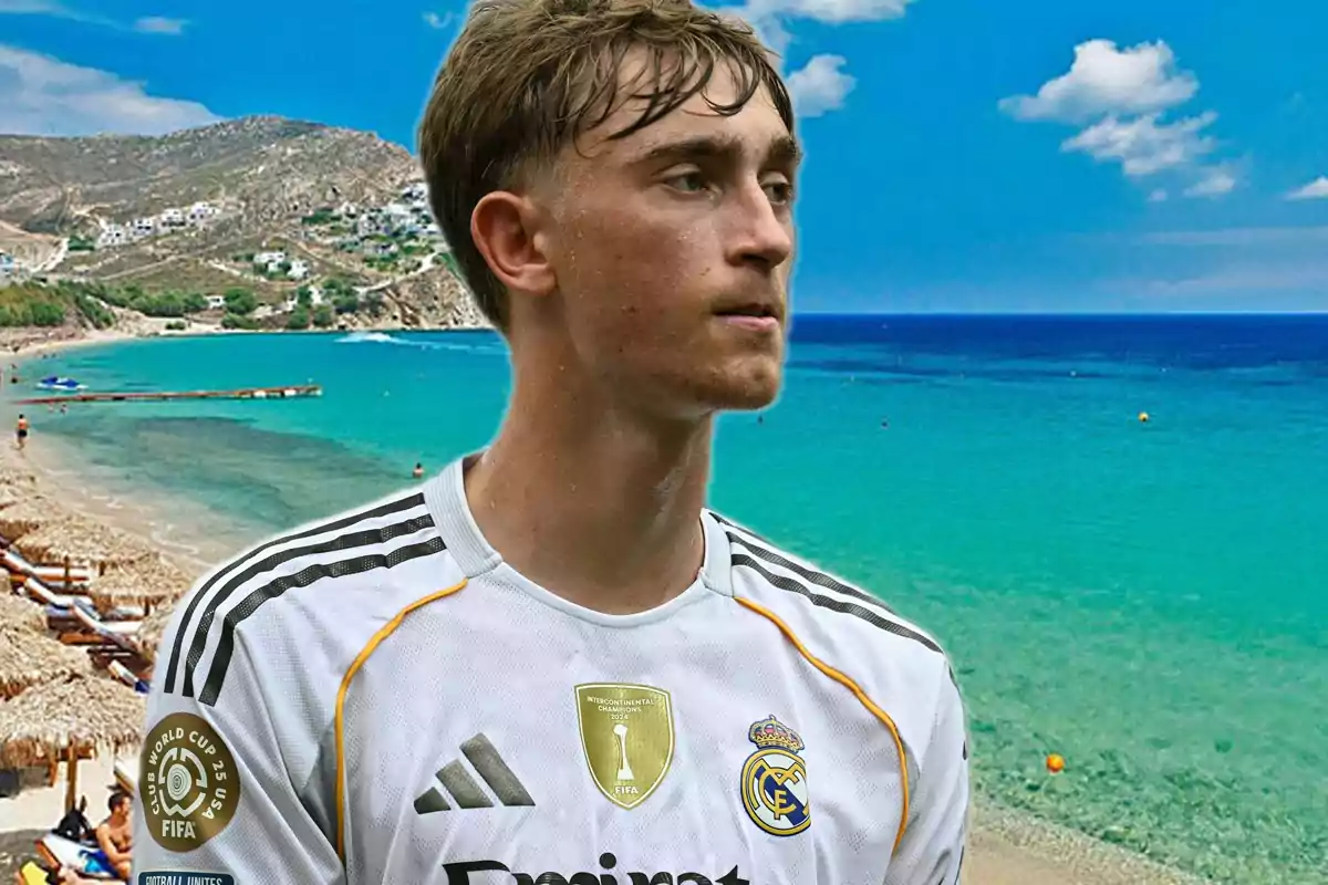 Joven con camiseta del Real Madrid posando frente a una playa de aguas turquesas y montañas al fondo