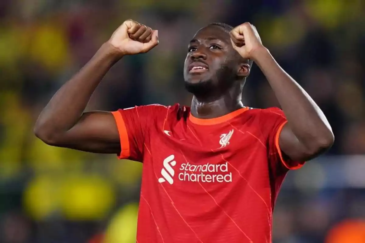 Liverpool footballer celebrating with arms raised during a match Liverpool footballer celebrating with arms raised during a match