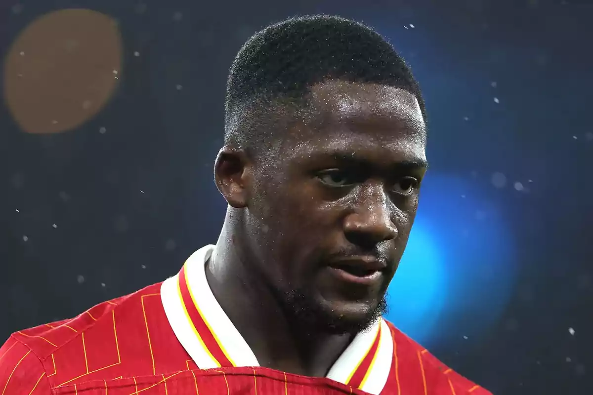 Soccer player wearing a red jersey with yellow details, sweating during a match in the rain Soccer player wearing a red jersey with yellow details, sweating during a match in the rain